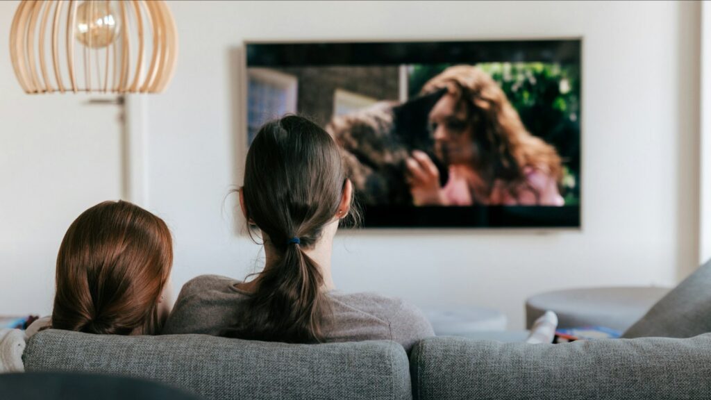 Bir kanepede televizyon izleyen iki kişi, arkadan görünüm (Apple TV Türkiye haberi, temsili görsel)