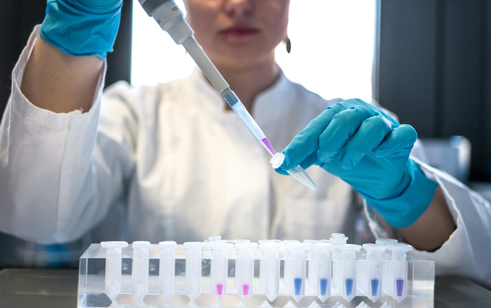 Araştırma üniversiteleri destek programı haberi için temsili görsel: laboratuvarda pipetle deney tüpleriyle çalışan bir bilim insanı