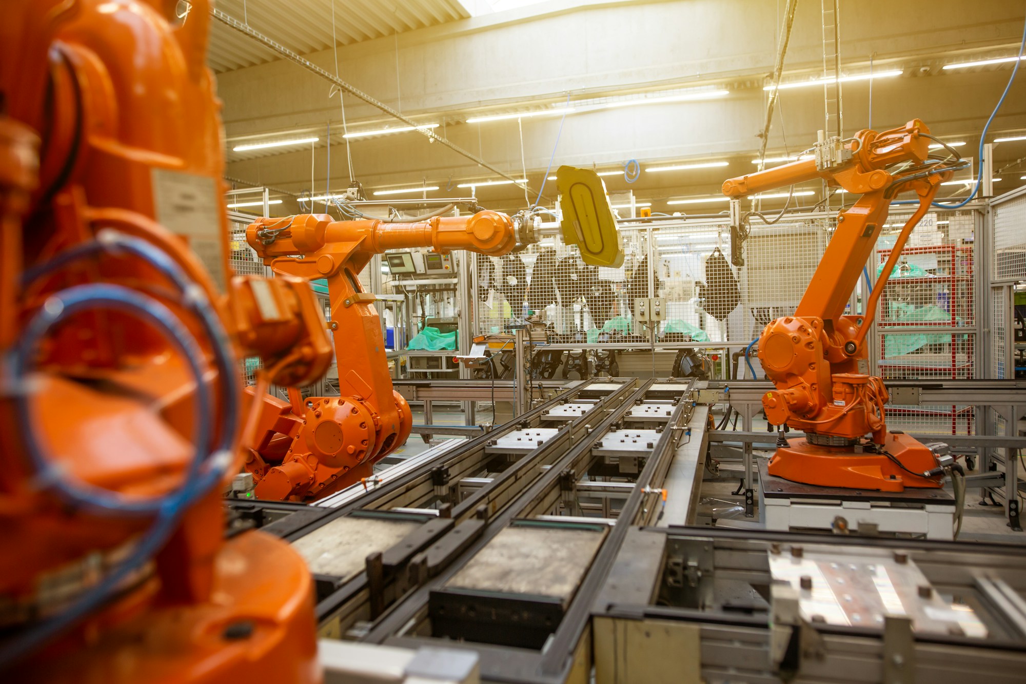Bir üretim hattında çalışan turuncu sanayi robotları