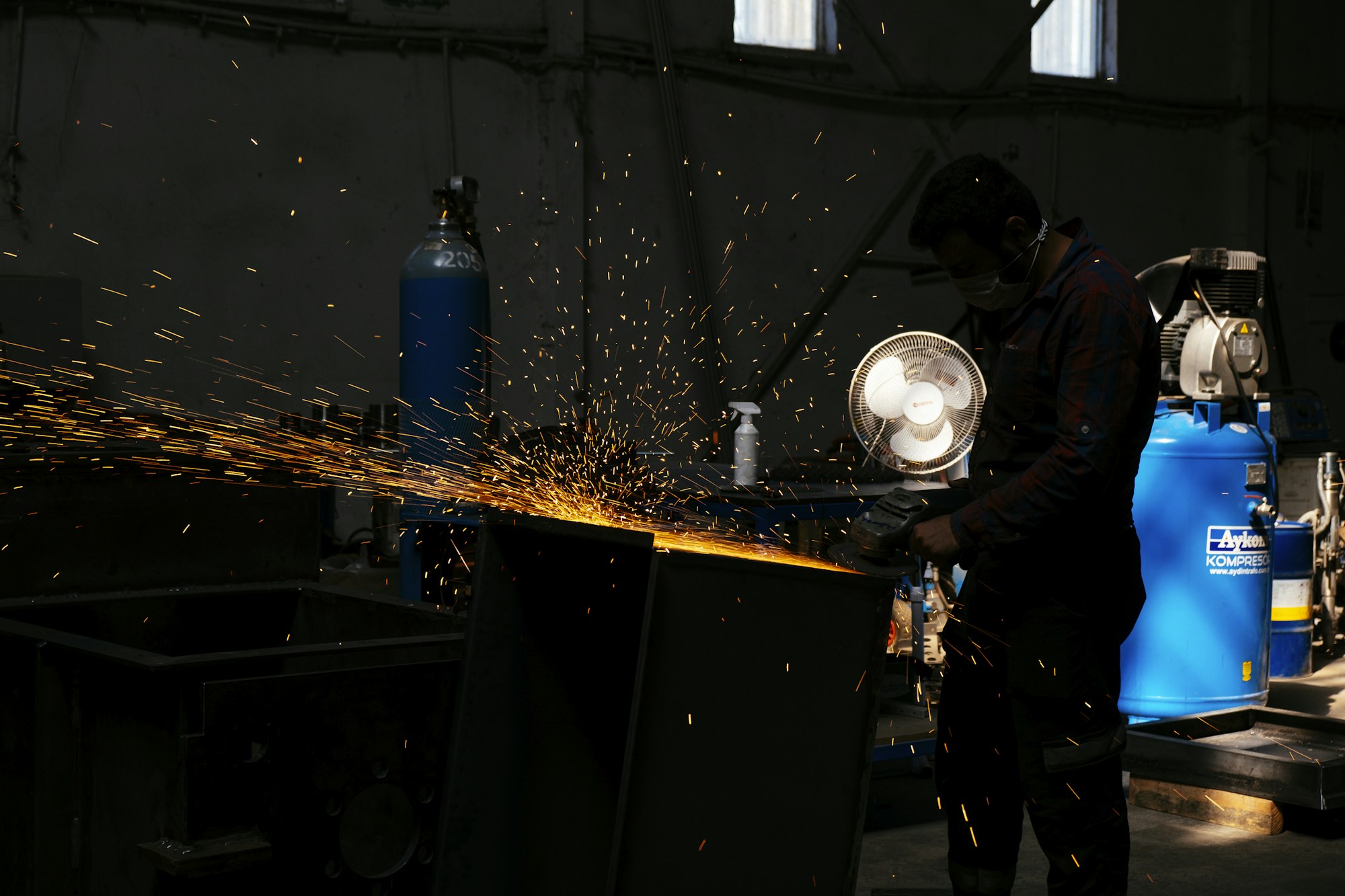 Bir atölyede metal keserken kıvılcım saçan taşlama makinesi