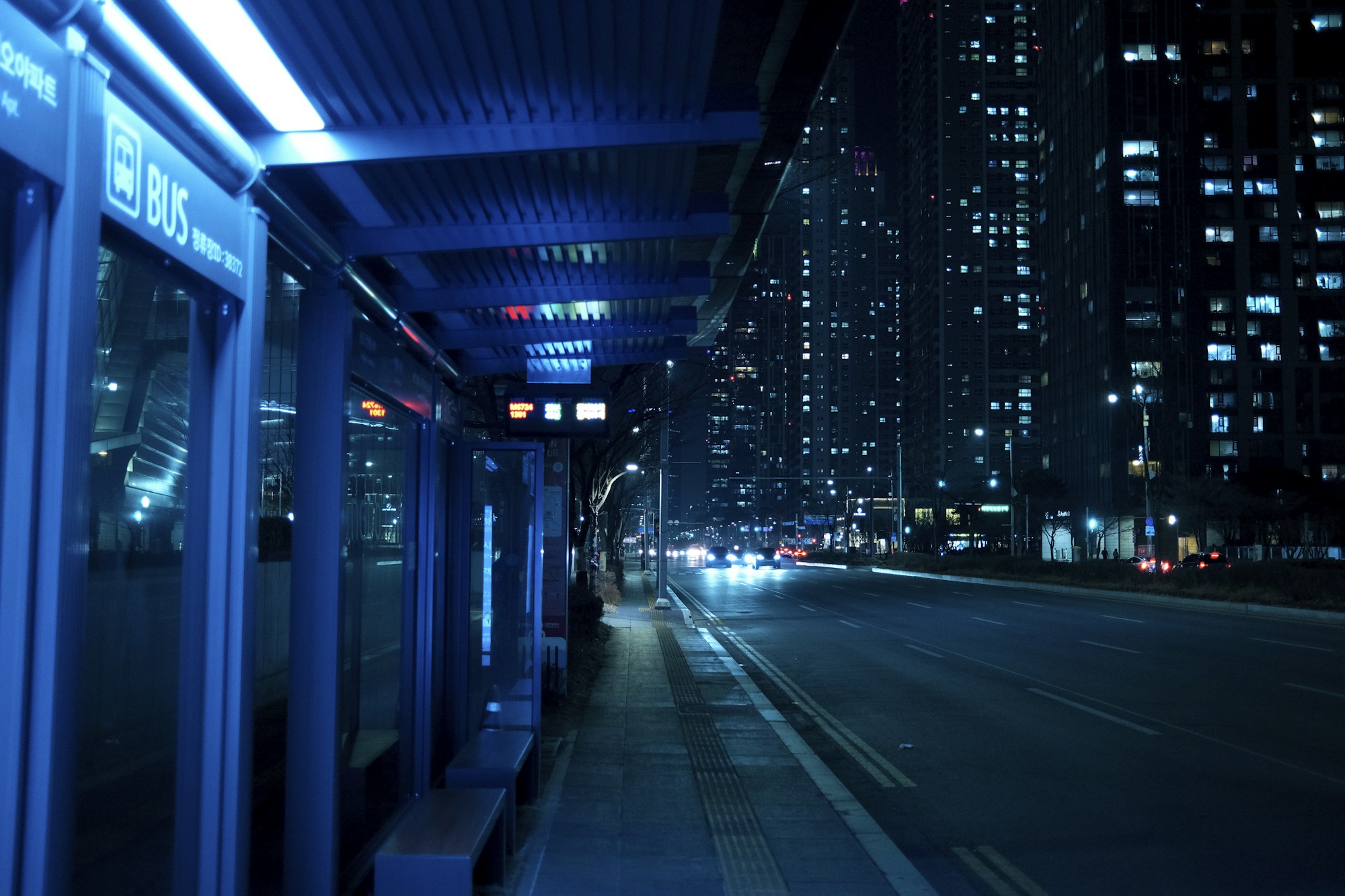 Gece yağmurlu bir caddede kapalı otobüs durağı (temsilî)