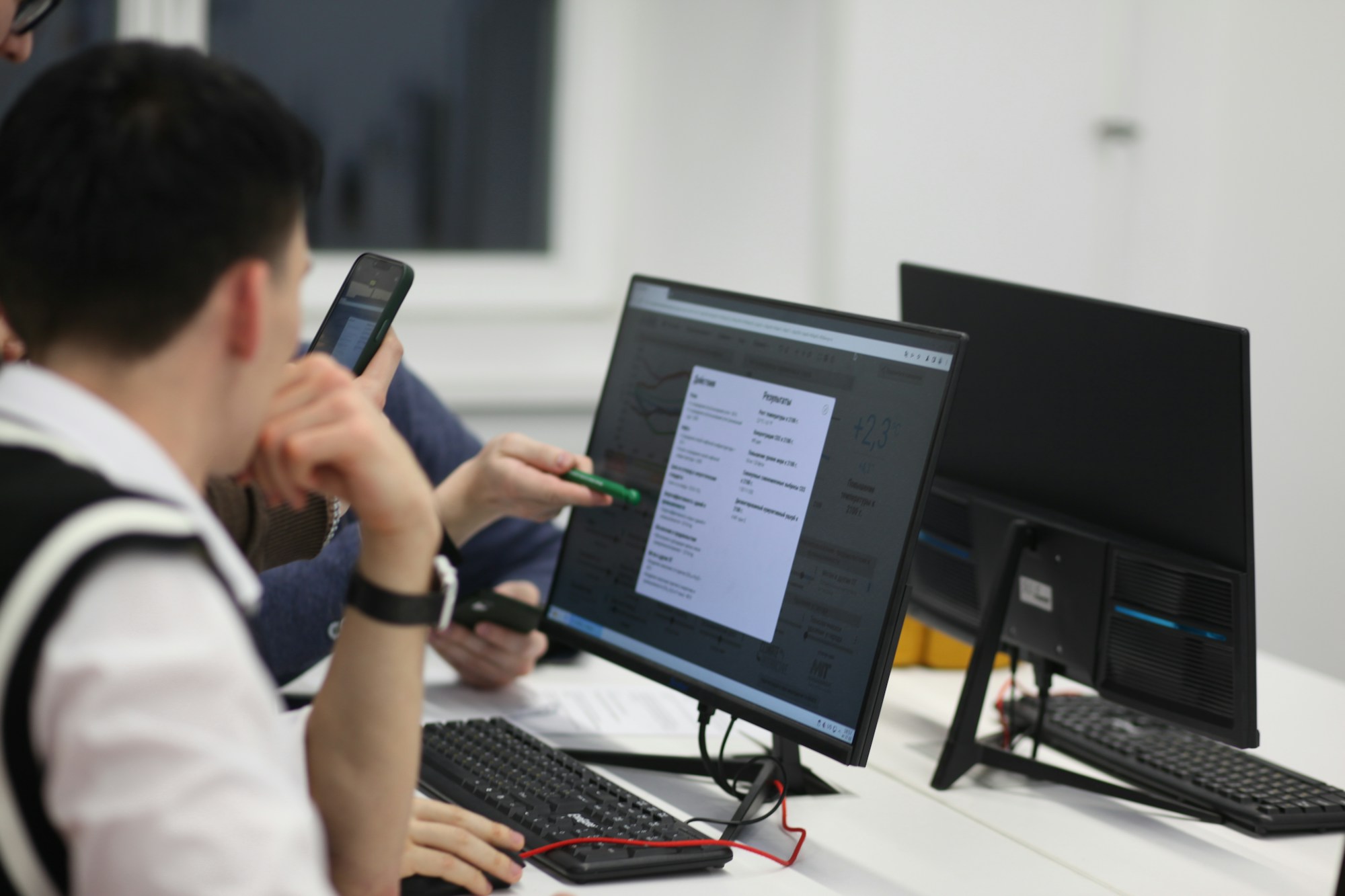 Bilgisayar başında telefonuna bakan bir öğrenci