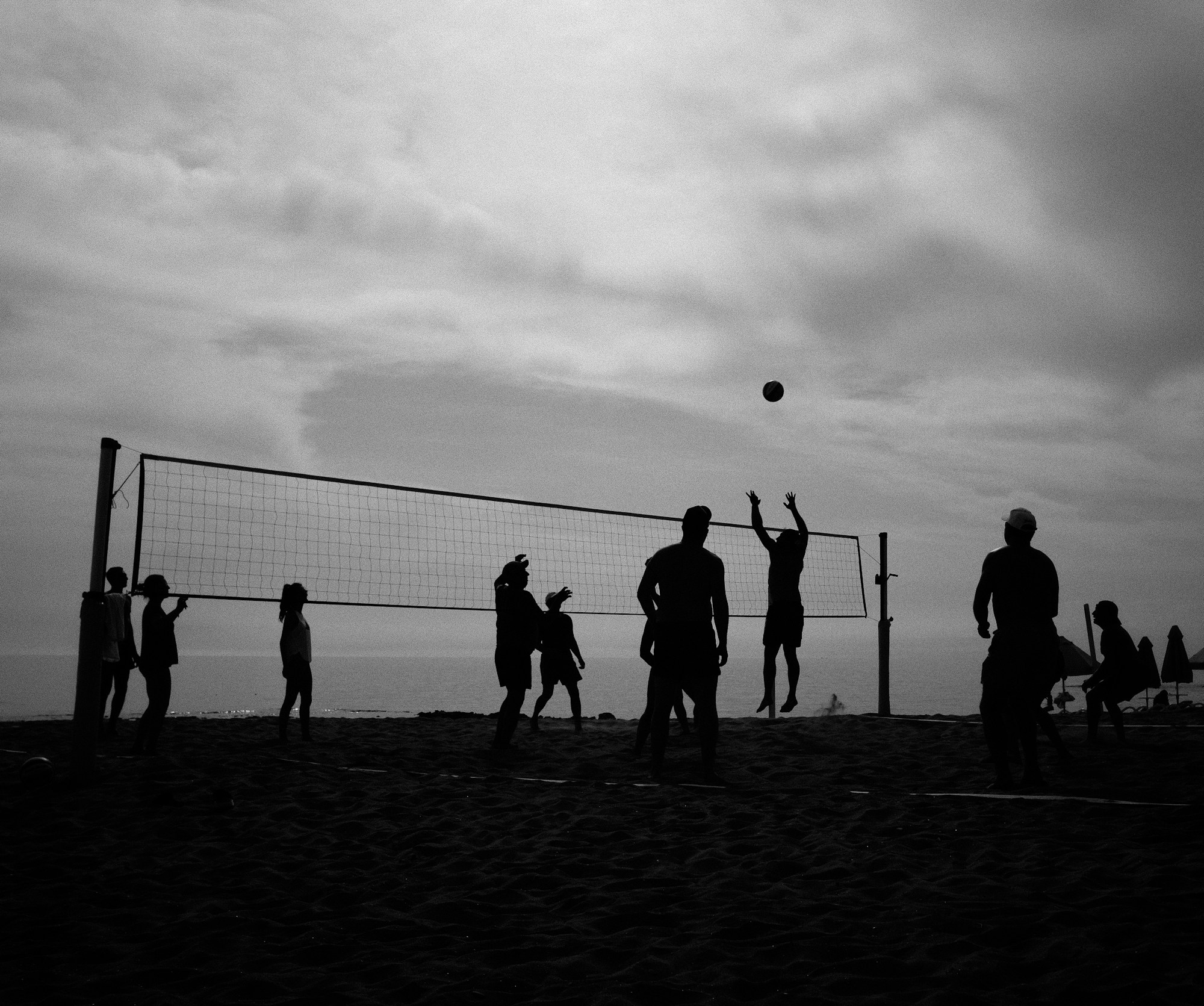 Gün batımında voleybol oynayan kişilerin siluetleri