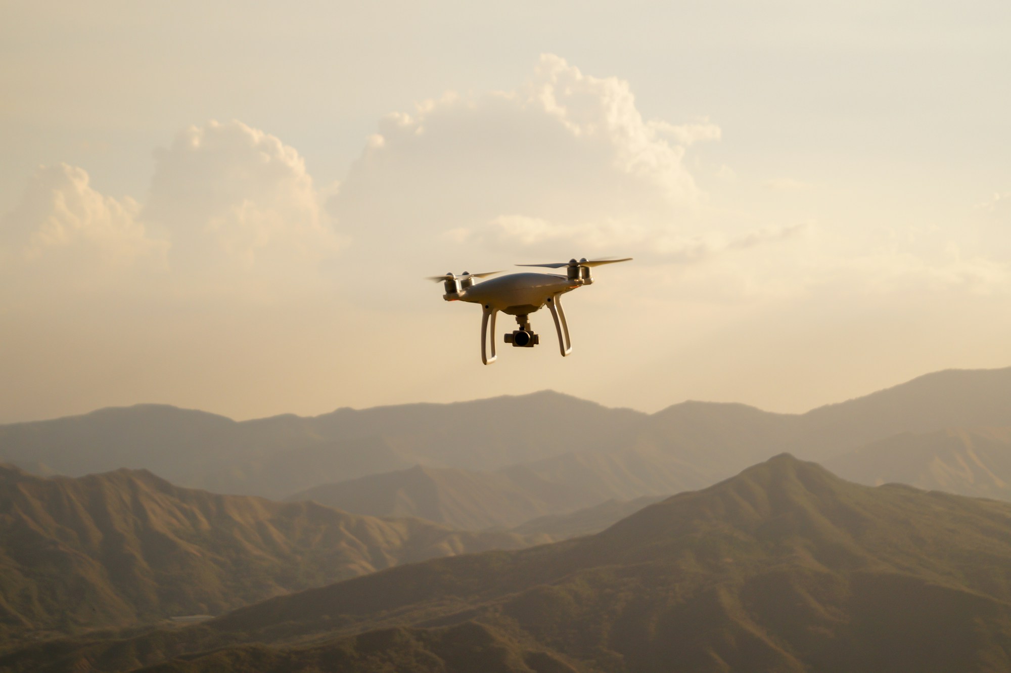 Gün batımında dağların üzerinde uçan bir dron